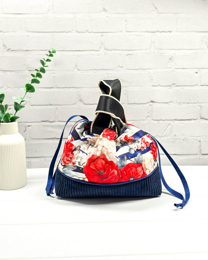 Projekttasche Alva in Größe S mit zwei Tragegriffen, roten Rosen auf blau-weiß gestreiftem Stoff und einem Taschenboden aus dunkelblauem Breitcord. Handgenäht in Bayern von Nadelmikado. 
