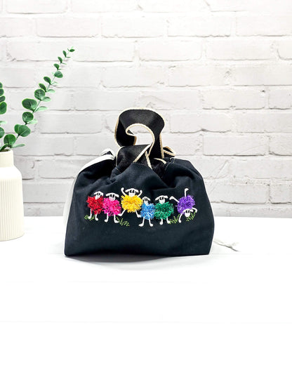 Projekttasche Alva S mit buntem Schafmotiv auf schwarzem Stoff, handgenäht in Bayern von Nadelmikado