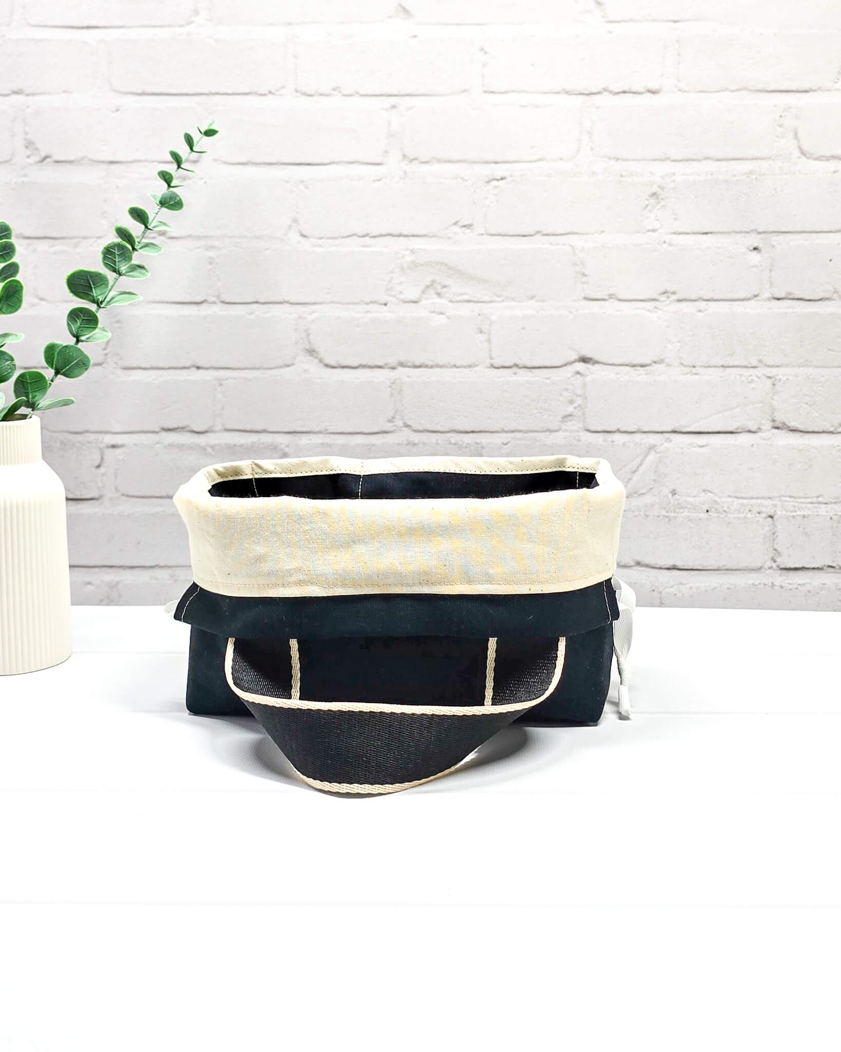 Projekttasche Alva S mit buntem Schafmotiv auf schwarzem Stoff, handgenäht in Bayern von Nadelmikado