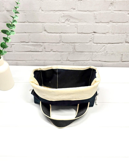 Projekttasche Alva S mit buntem Schafmotiv auf schwarzem Stoff, handgenäht in Bayern von Nadelmikado