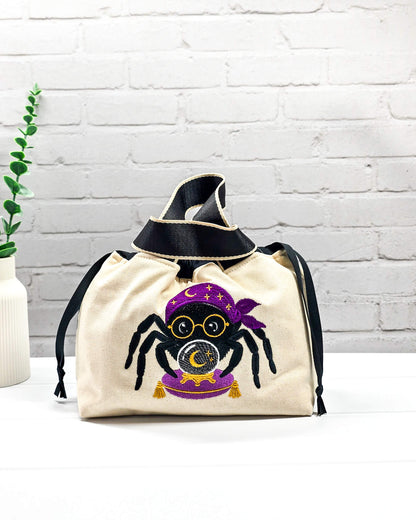 Projekttasche Alva S aus hellem Canvas mit gestickter Wahrsager Spinne und Kristallkugel, Henkeln und schwarzem Kordelzugkragen. Handgenäht in Bayern von Nadelmikado.