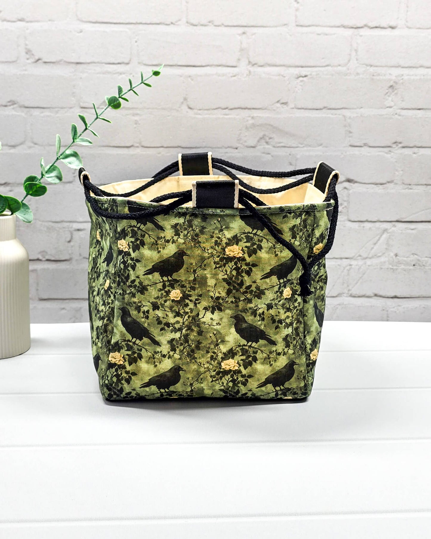 Mittlere grüne Projekttasche mit Kordelzug im Rice Bag Stil, gemustert mit Raben und Rosen, genutzt als Strickbeutel für ein Tuchprojekt mit bis zu 400g Wolle. Handgenäht in Bayern  von Nadelmikado.
