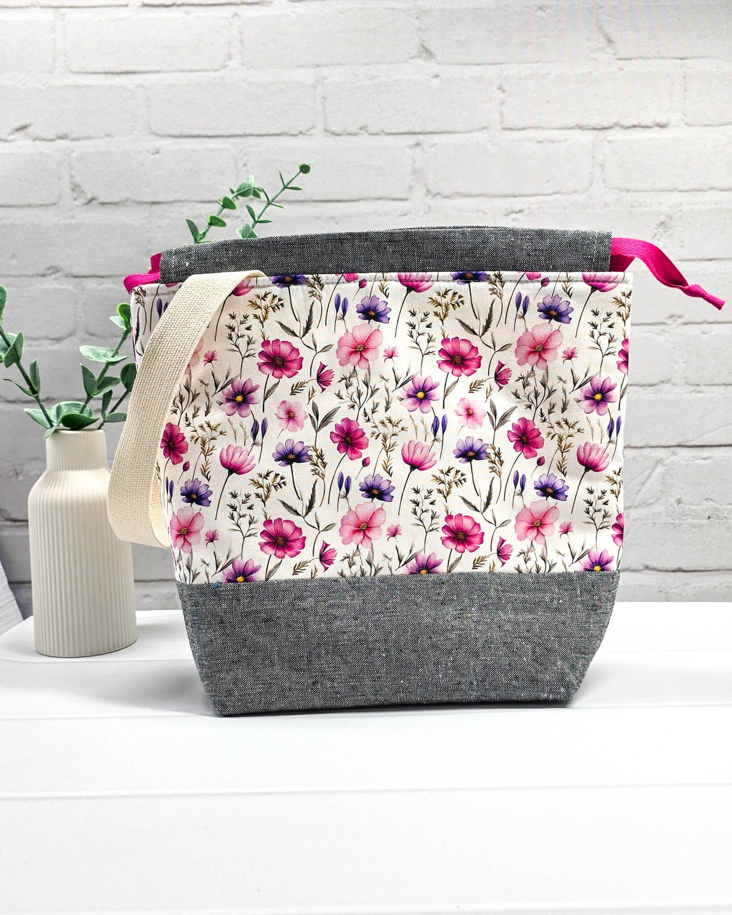 Handgenähte Projekttasche mit zartem Blumenmuster in Pink und Lila auf hellem Stoff mit graumeliertem Boden. Handmade in Bayern von Nadelmikado.