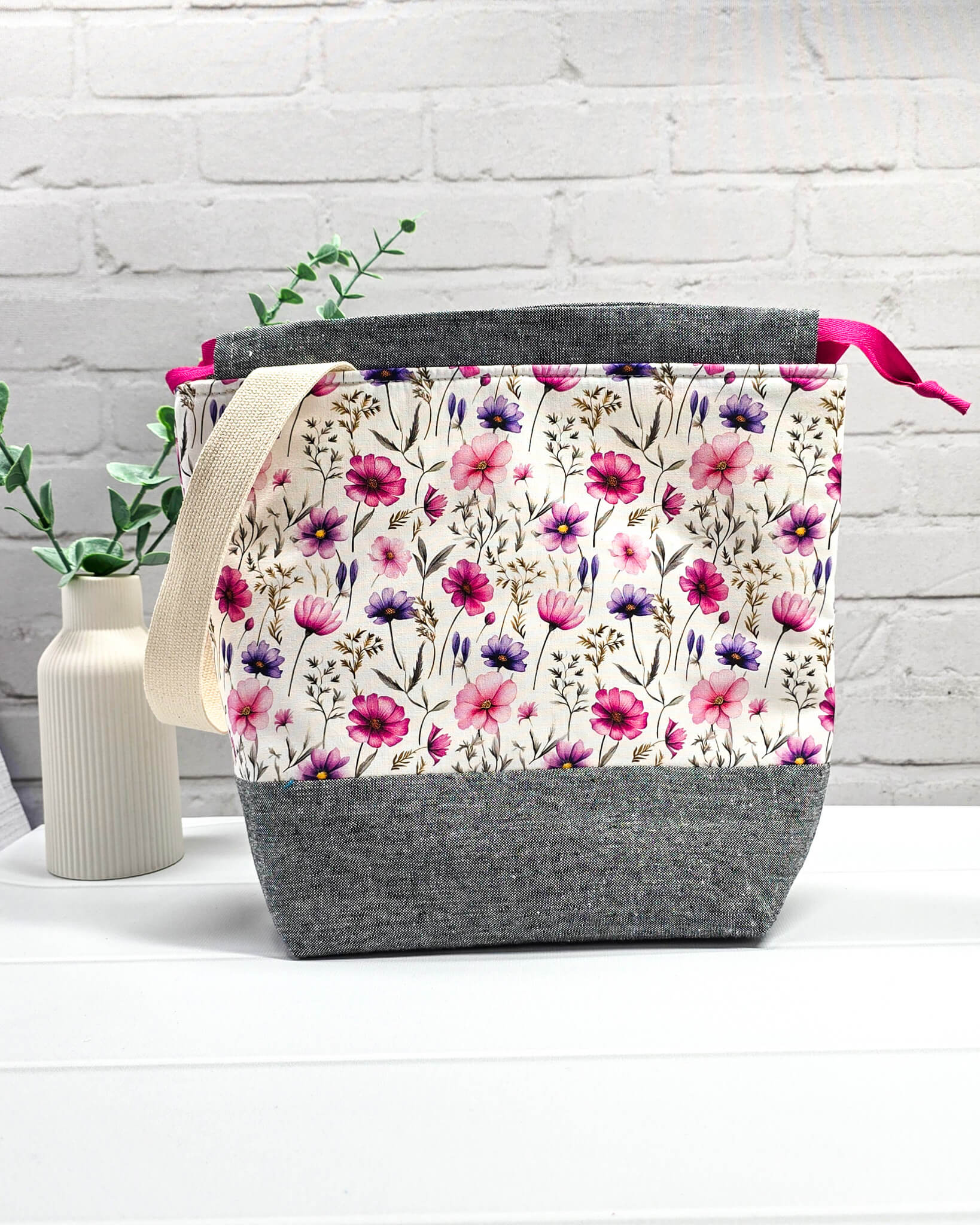 Handgenähte Projekttasche mit zartem Blumenmuster in Pink und Lila auf hellem Stoff mit graumeliertem Boden. Handmade in Bayern von Nadelmikado.