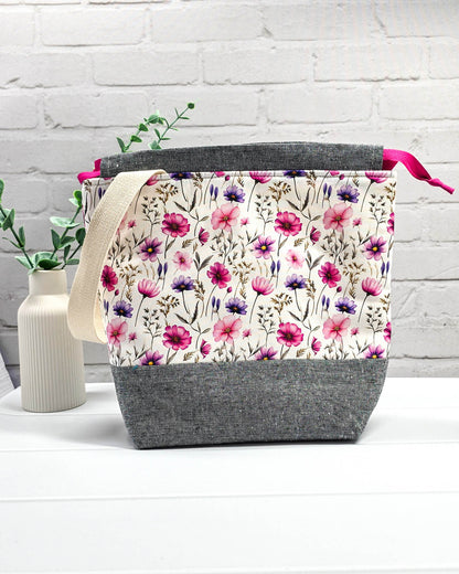 Handgenähte Projekttasche mit zartem Blumenmuster in Pink und Lila auf hellem Stoff mit graumeliertem Boden. Handmade in Bayern von Nadelmikado.