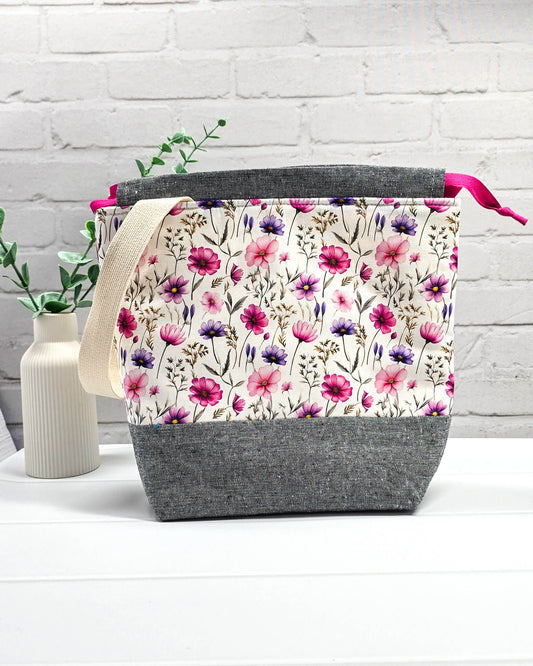Handgenähte Projekttasche mit zartem Blumenmuster in Pink und Lila auf hellem Stoff mit graumeliertem Boden. Handmade in Bayern von Nadelmikado.