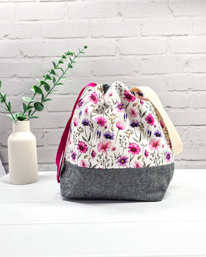 Handgenähte Projekttasche mit zartem Blumenmuster in Pink und Lila auf hellem Stoff mit graumeliertem Boden. Handmade in Bayern von Nadelmikado.