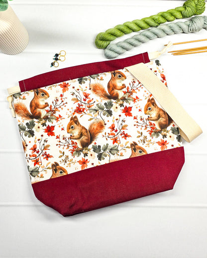 Handgenähte Projekttasche mit herbstlichem Eichhörnchen-Muster auf hellem Grund mit weinrotem Boden. Handmade in Bayern von Nadelmikado.