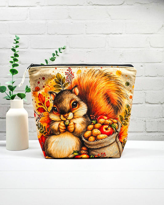 Strickbeutel Größe M mit Eichhörnchen, Herbstlaub und Erntekorb auf hellem Grund sowie schwarzem Reißverschluss. Handgenäht in Bayern von Nadelmikado.