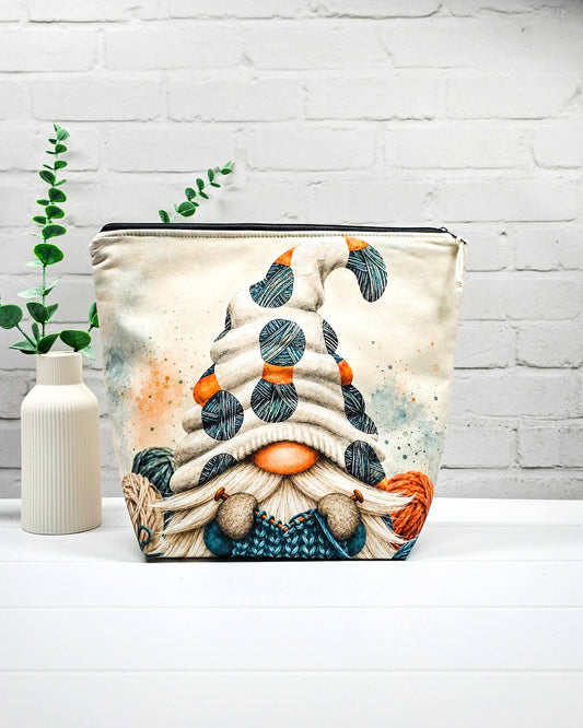 Strickprojekttasche Größe M mit Wichtel, heller Mütze und Wollknäueln in Petrol, Orange und Dunkelgrau sowie schwarzem Reißverschluss. Handgenäht in Bayern von Nadelmikado.
