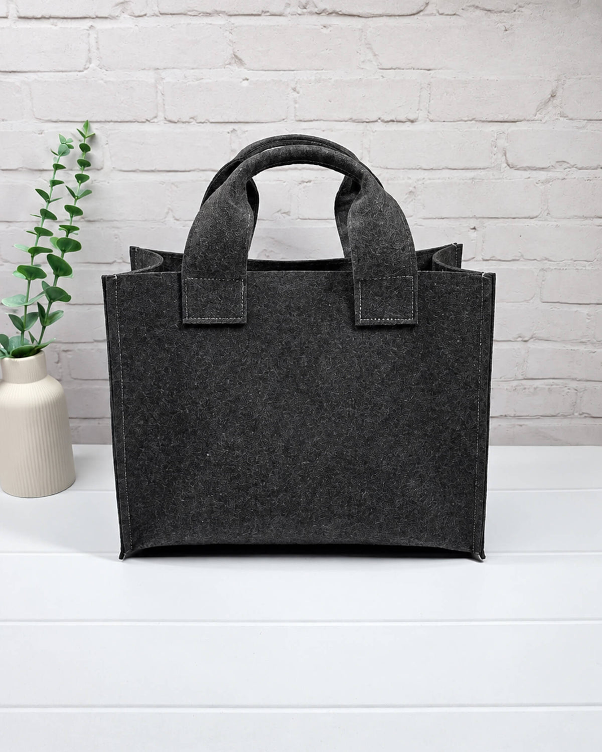 Stricktasche Größe M aus anthrazitfarbenem Filz mit großer bordeauxroter Außentasche und zwei kurzen Henkeln. Handgenäht in Bayern von Nadelmikado.