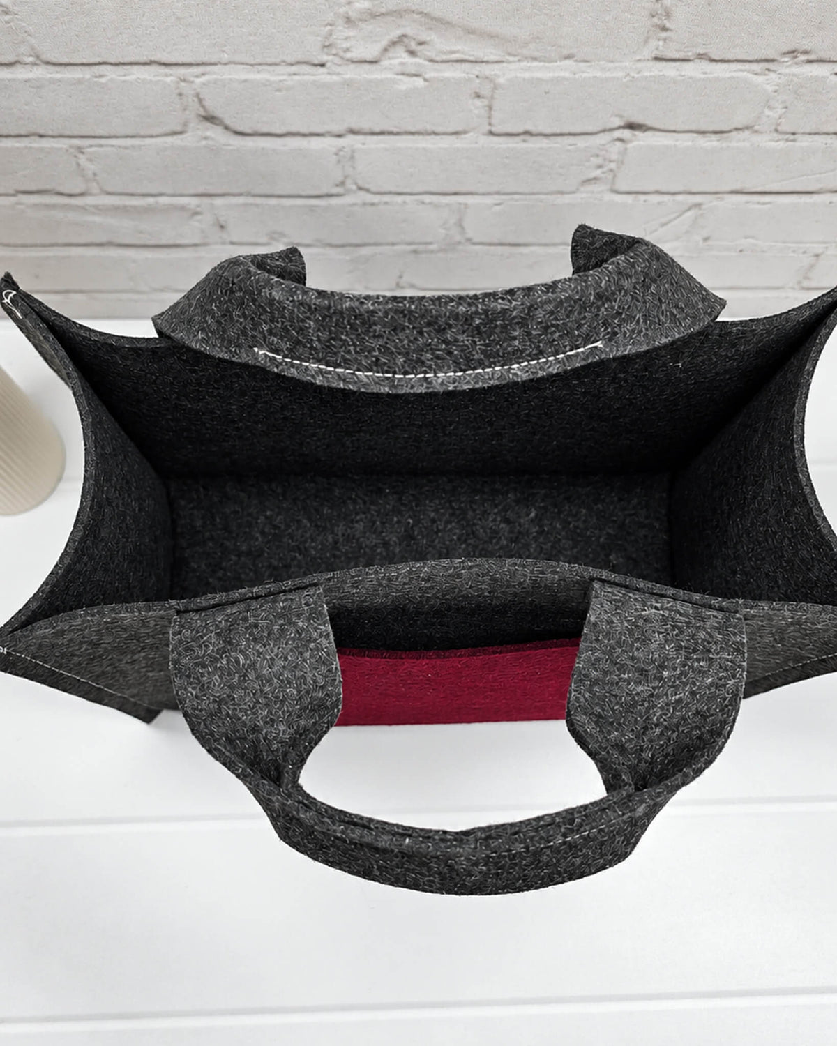 Stricktasche Größe M aus anthrazitfarbenem Filz mit großer bordeauxroter Außentasche und zwei kurzen Henkeln. Handgenäht in Bayern von Nadelmikado.