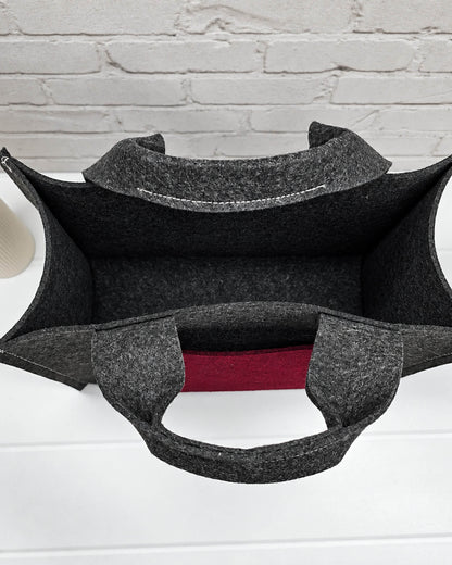 Stricktasche Größe M aus anthrazitfarbenem Filz mit großer bordeauxroter Außentasche und zwei kurzen Henkeln. Handgenäht in Bayern von Nadelmikado.