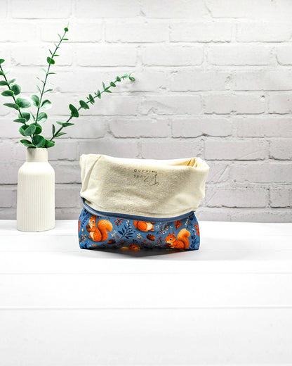 Projekttasche Größe M mit Reißverschluss aus blauem Baumwollstoff mit orangefarbenen Eichhörnchen, Eicheln und Blättern zur Aufbewahrung von Wolle und Strickprojekten. Handgenäht in Bayern von Nadelmikado.