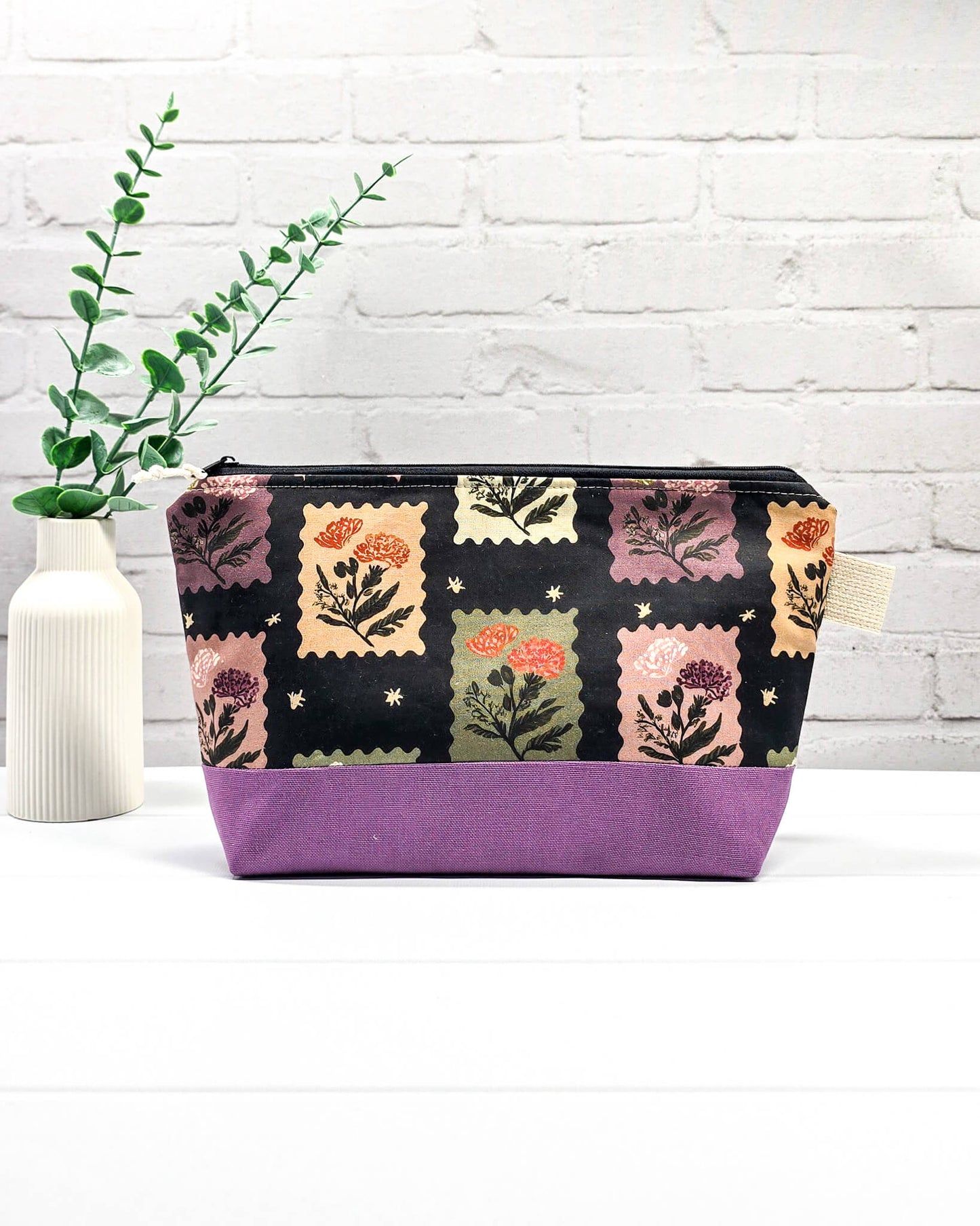 Stricktasche mit Briefmarken- und Blütenmuster, lila Canvas-Boden und Reißverschluss. Platz für 200g Wolle. Handgenäht in Bayern von Nadelmikado.