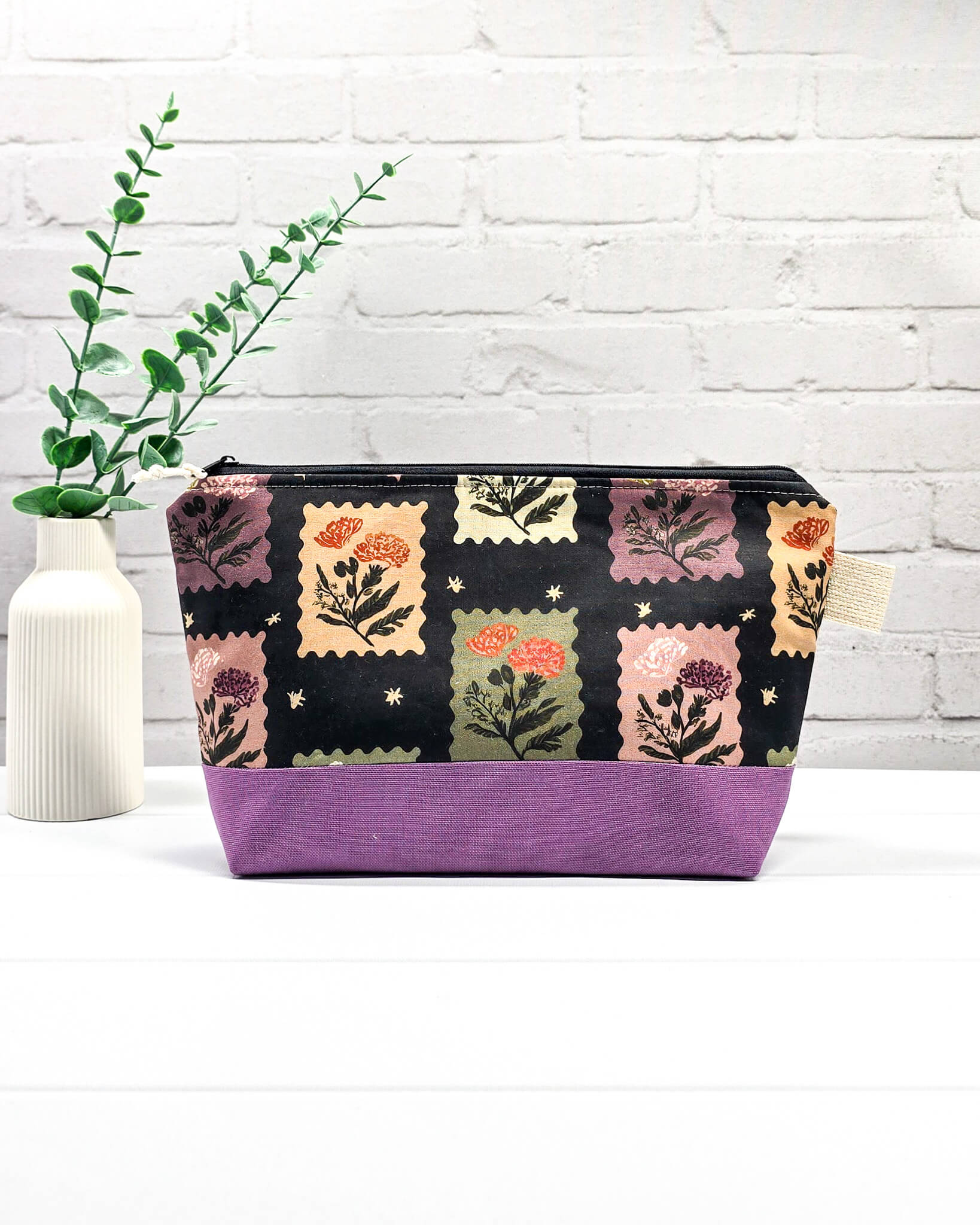 Stricktasche mit Briefmarken- und Blütenmuster, lila Canvas-Boden und Reißverschluss. Platz für 200g Wolle. Handgenäht in Bayern von Nadelmikado.