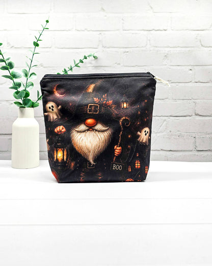 Projekttasche Isvind Größe S mit Halloweenwichtel in schwarzem Hexenhut, weißem Bart, leuchtender Laterne und kleinen Gespenstern vor dunkler Häuserkulisse. Stricktasche mit Reißverschluss für kleine Strickprojekte. Handgenäht in Bayern von Nadelmikado.