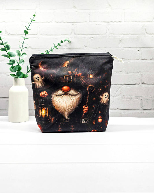 Projekttasche Isvind Größe S mit Halloweenwichtel in schwarzem Hexenhut, weißem Bart, leuchtender Laterne und kleinen Gespenstern vor dunkler Häuserkulisse. Stricktasche mit Reißverschluss für kleine Strickprojekte. Handgenäht in Bayern von Nadelmikado.