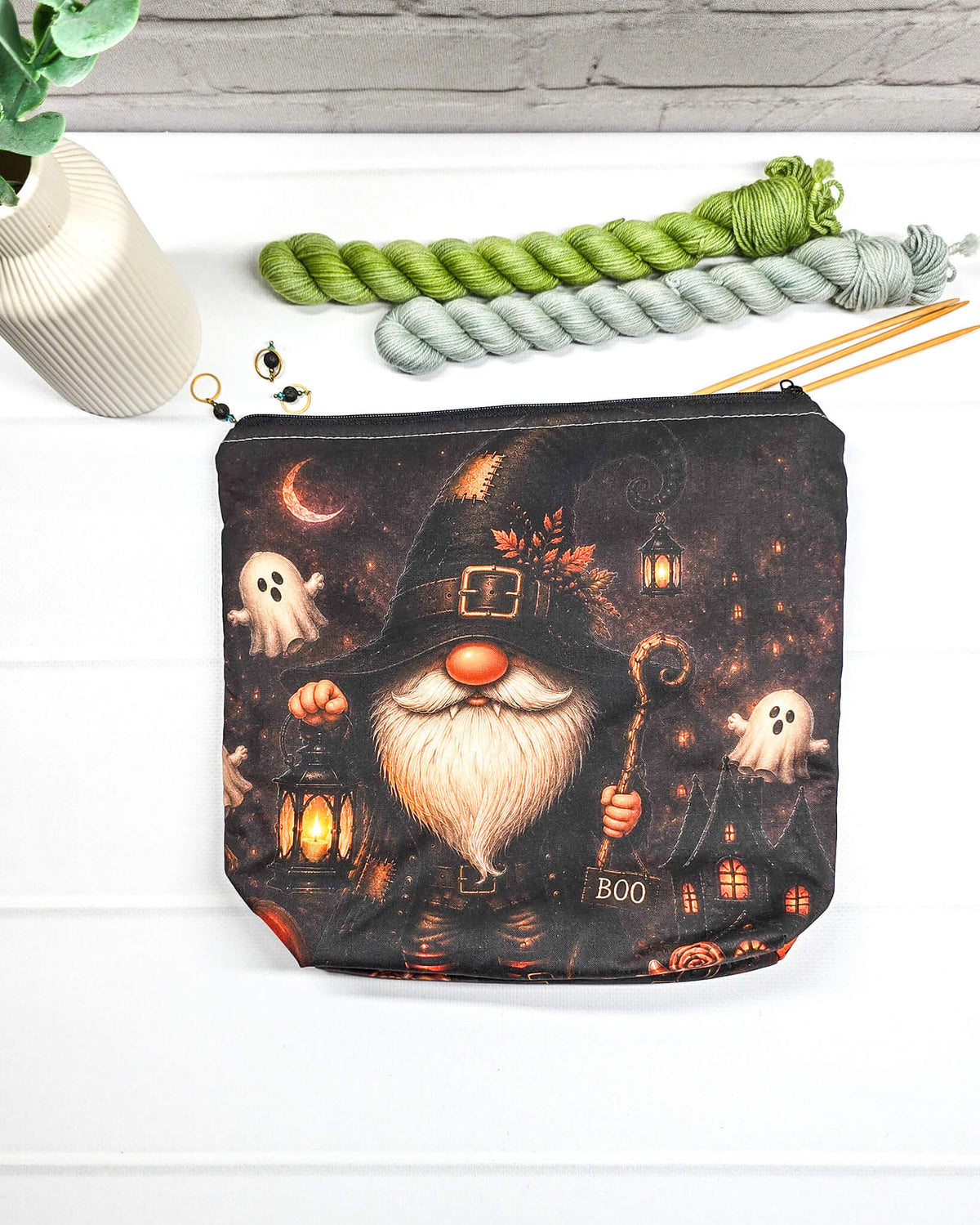 Projekttasche Isvind Größe S mit Halloweenwichtel in schwarzem Hexenhut, weißem Bart, leuchtender Laterne und kleinen Gespenstern vor dunkler Häuserkulisse. Stricktasche mit Reißverschluss für kleine Strickprojekte. Handgenäht in Bayern von Nadelmikado.