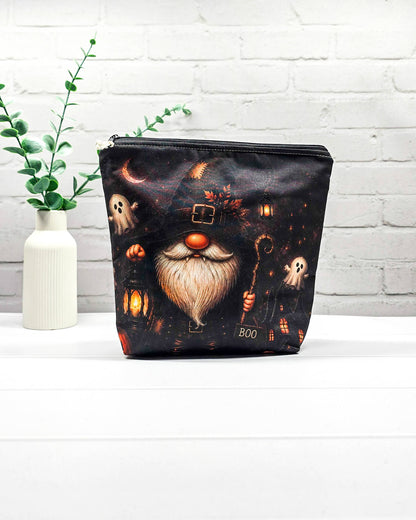 Projekttasche Isvind Größe S mit Halloweenwichtel in schwarzem Hexenhut, weißem Bart, leuchtender Laterne und kleinen Gespenstern vor dunkler Häuserkulisse. Stricktasche mit Reißverschluss für kleine Strickprojekte. Handgenäht in Bayern von Nadelmikado.