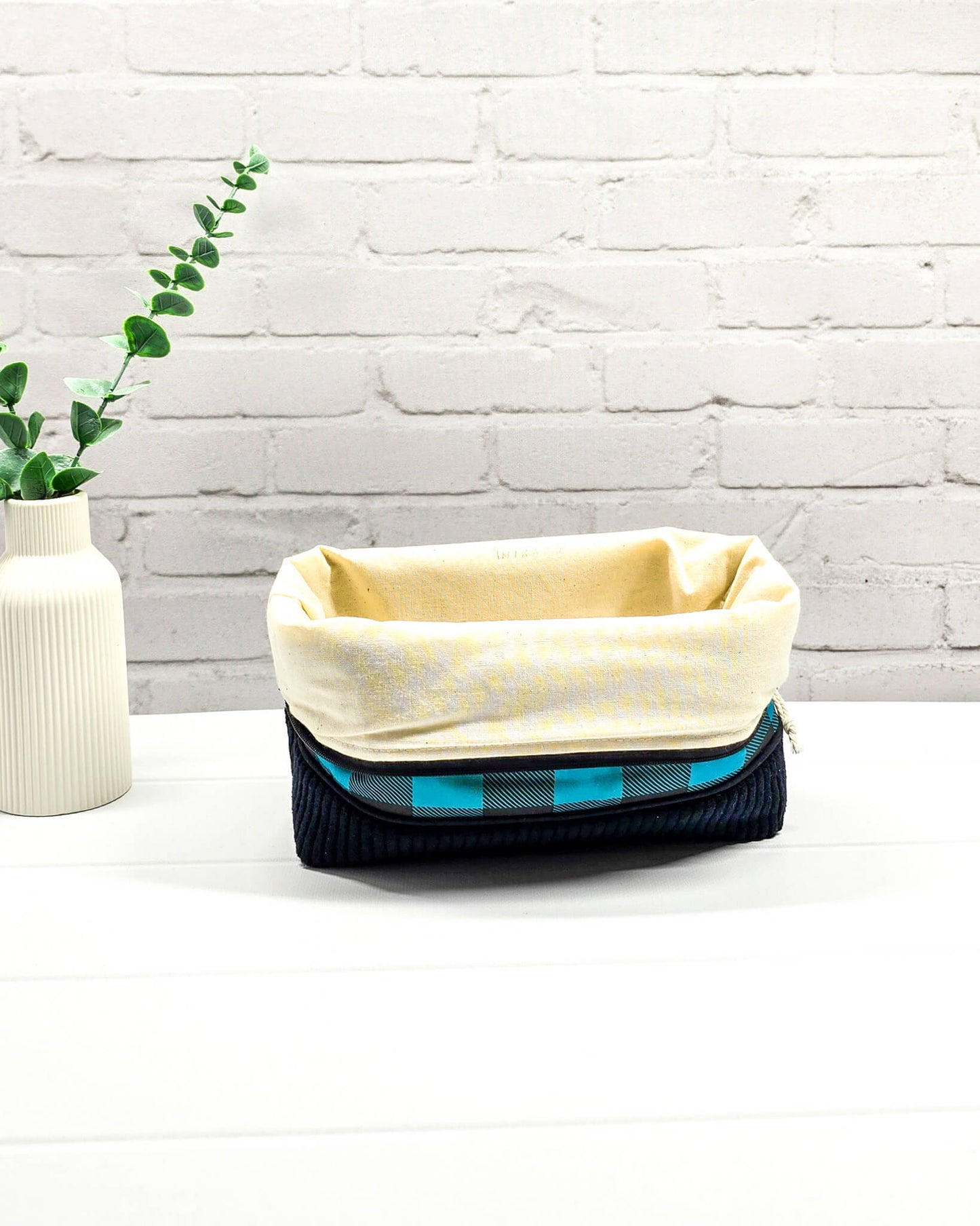 Handgemachte Projekttasche Isvind in Größe S mit blau-schwarzem Karomuster und einem Taschenboden aus schwarzem Breitcord. Handgenäht in Bayern von Nadelmikado. 