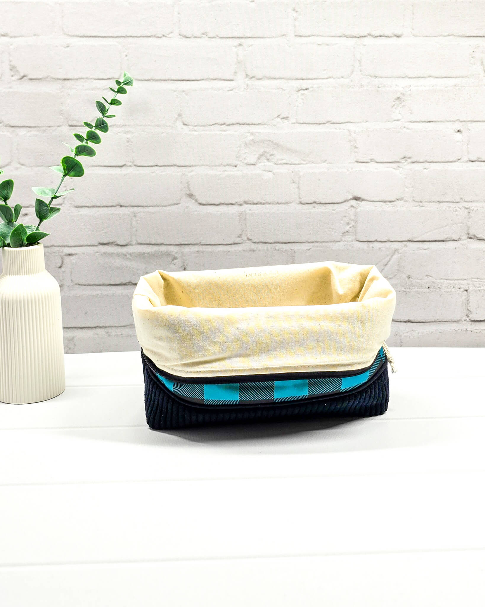 Handgemachte Projekttasche Isvind in Größe S mit blau-schwarzem Karomuster und einem Taschenboden aus schwarzem Breitcord. Handgenäht in Bayern von Nadelmikado. 