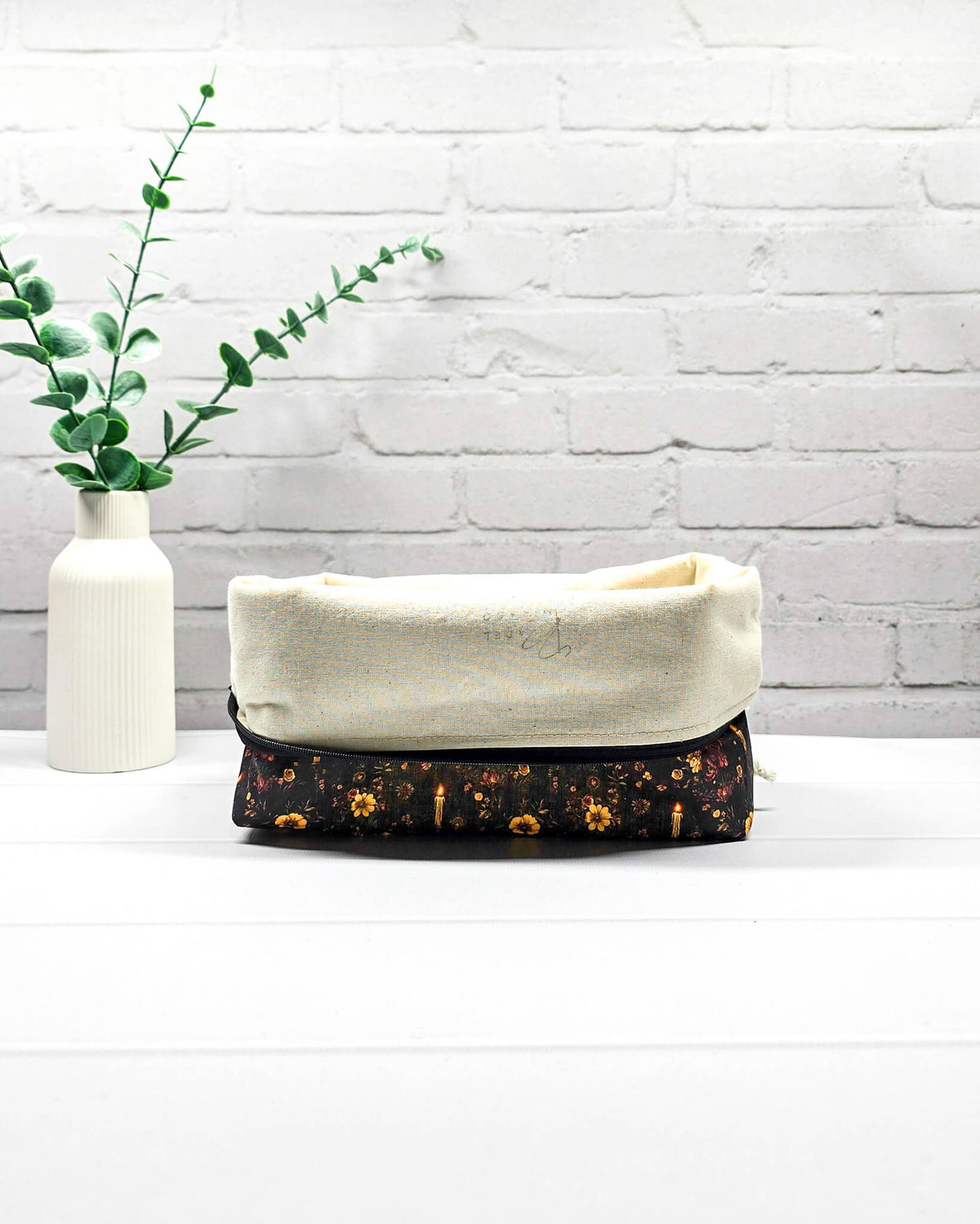 Projekttasche Isvind Größe S aus schwarzem Stoff mit goldgelben und orangefarbenen Blumen, kleinen leuchtenden Kerzen und Reißverschluss. Für Strickprojekte bis 200 g Wolle. Handgenäht in Bayern von Nadelmikado.