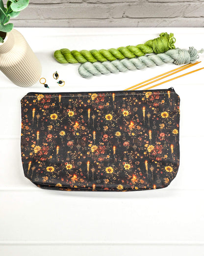 Projekttasche Isvind Größe S aus schwarzem Stoff mit goldgelben und orangefarbenen Blumen, kleinen leuchtenden Kerzen und Reißverschluss. Für Strickprojekte bis 200 g Wolle. Handgenäht in Bayern von Nadelmikado.
