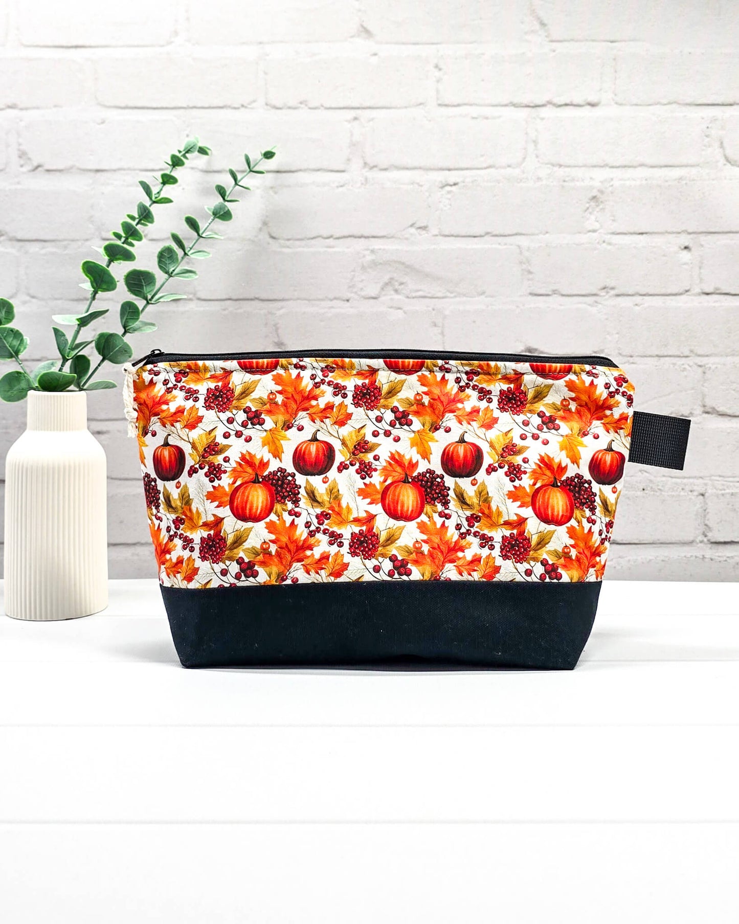 Stricktasche mit Kürbis- und Herbstlaub-Motiv, schwarzem Canvas-Boden und Reißverschluss. Platz für 200g Wolle. Handgenäht in Bayern von Nadelmikado.