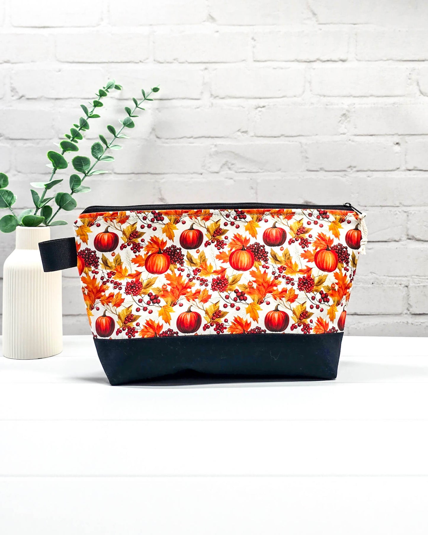 Stricktasche mit Kürbis- und Herbstlaub-Motiv, schwarzem Canvas-Boden und Reißverschluss. Platz für 200g Wolle. Handgenäht in Bayern von Nadelmikado.