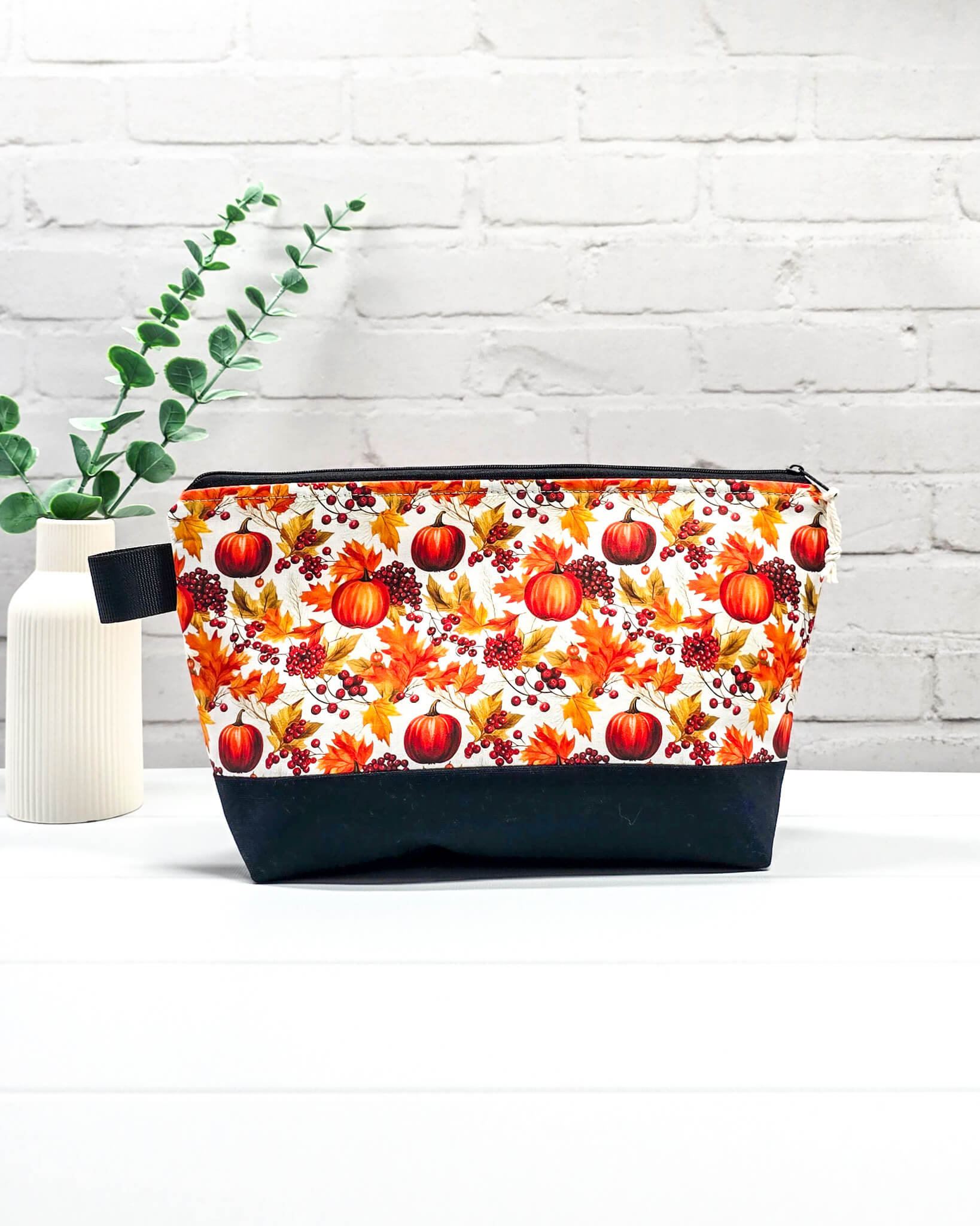 Stricktasche mit Kürbis- und Herbstlaub-Motiv, schwarzem Canvas-Boden und Reißverschluss. Platz für 200g Wolle. Handgenäht in Bayern von Nadelmikado.