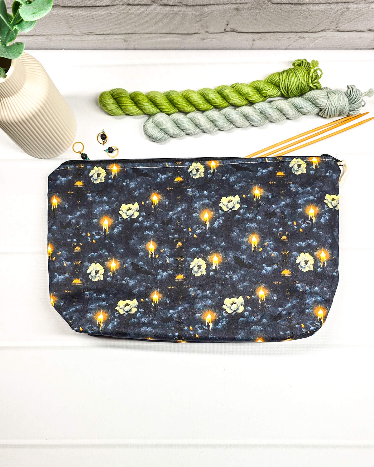 Projekttasche Isvind Größe S aus dunkelblau-schwarzem Stoff mit leuchtenden Kerzen, hellen Blüten und geheimnisvollem Muster. Mit Reißverschluss für kleine Strickprojekte. Handgenäht in Bayern von Nadelmikado.