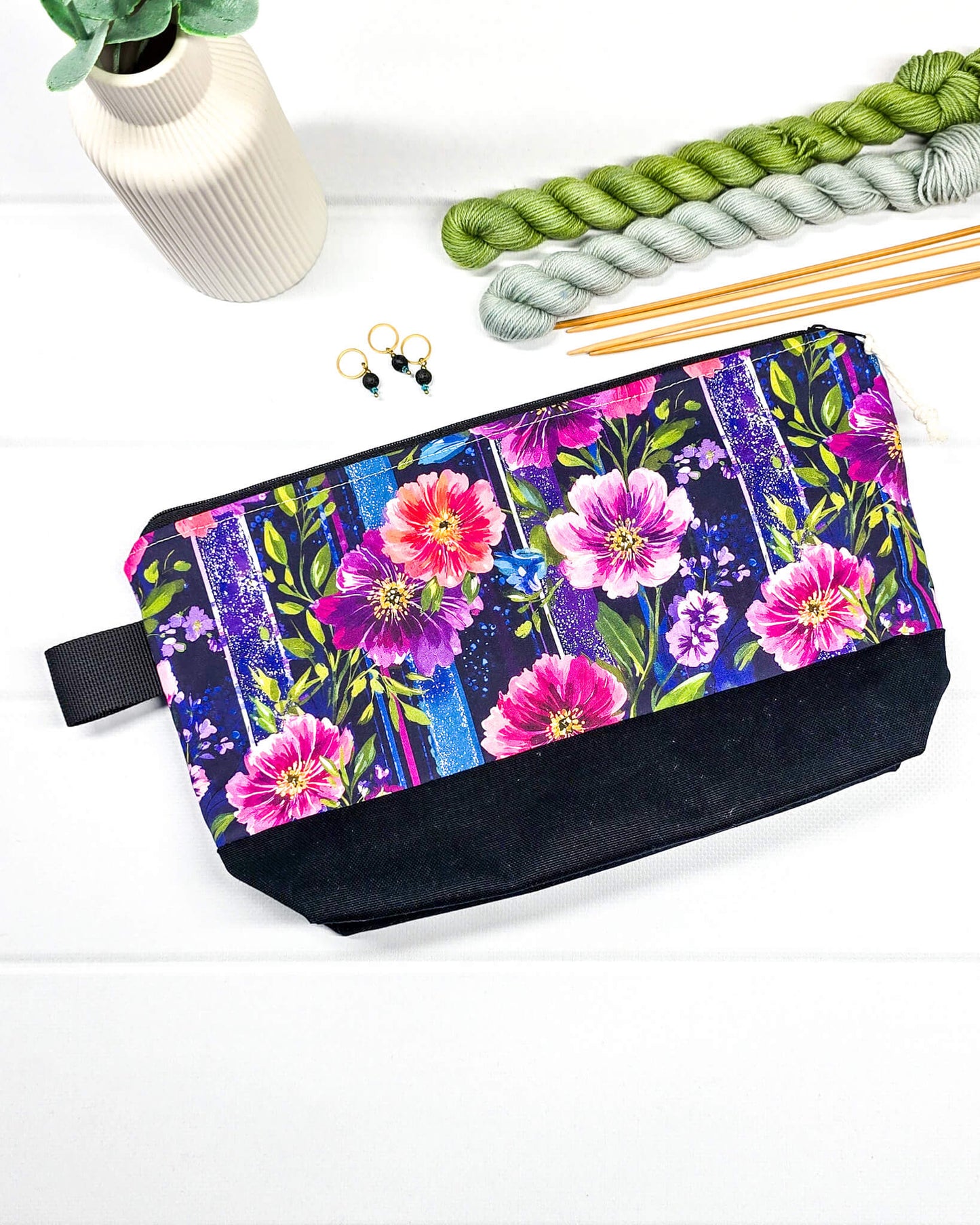 Stricktasche mit pink-violettem Blütenmuster auf Streifendekor, schwarzem Canvas-Boden und Reißverschluss. Platz für 200g Wolle. Handgenäht in Bayern von Nadelmikado.