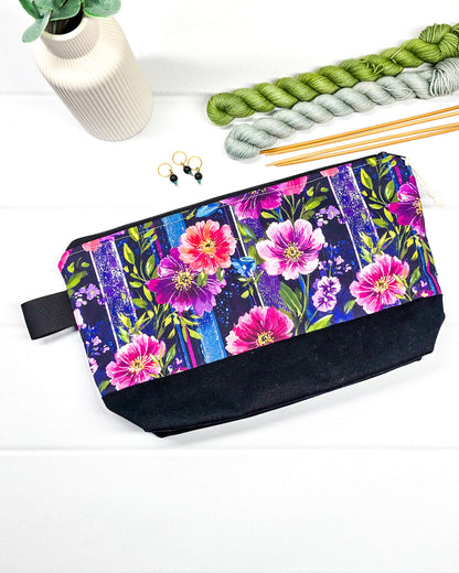 Stricktasche mit pink-violettem Blütenmuster auf Streifendekor, schwarzem Canvas-Boden und Reißverschluss. Platz für 200g Wolle. Handgenäht in Bayern von Nadelmikado.