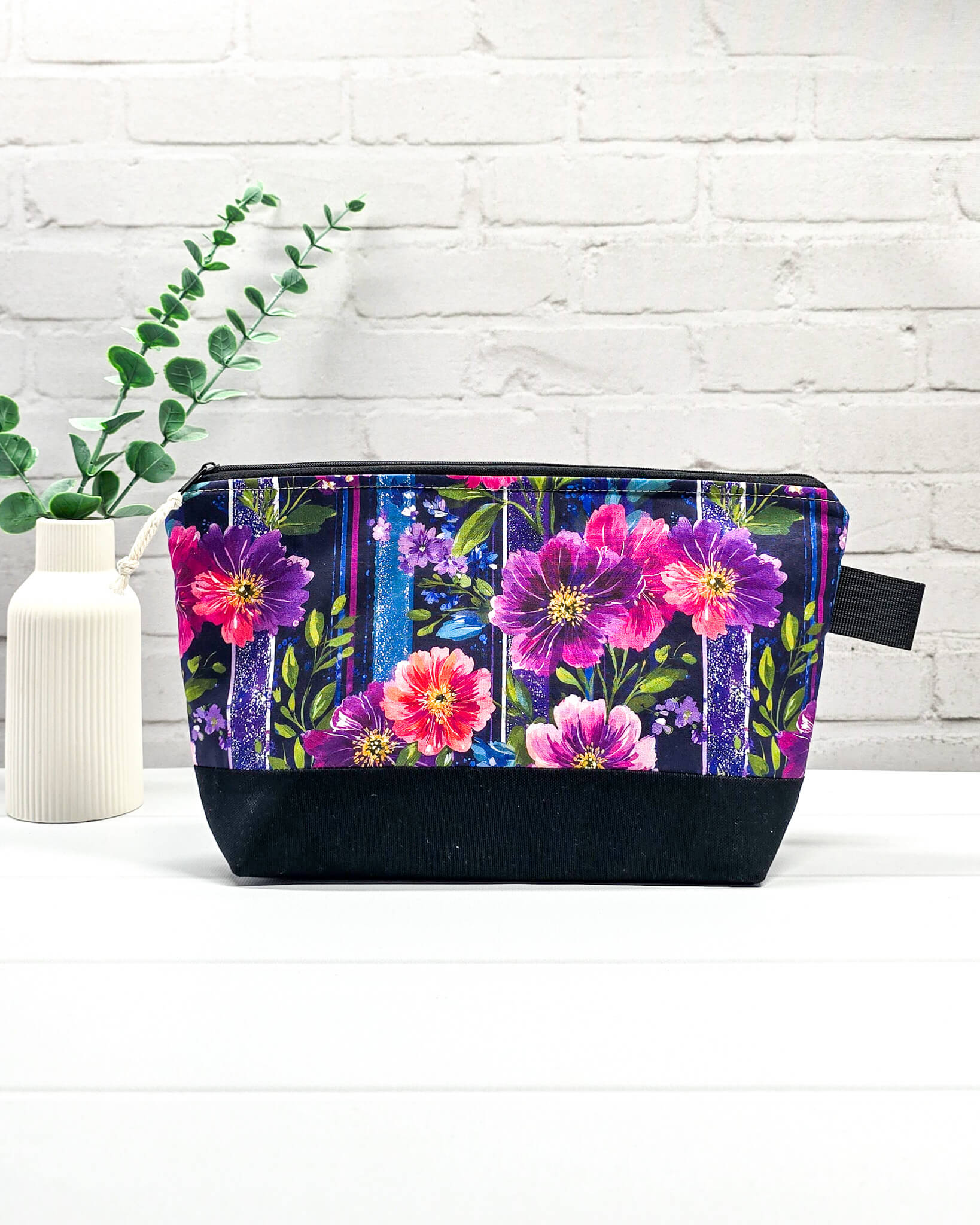 Stricktasche mit pink-violettem Blütenmuster auf Streifendekor, schwarzem Canvas-Boden und Reißverschluss. Platz für 200g Wolle. Handgenäht in Bayern von Nadelmikado.