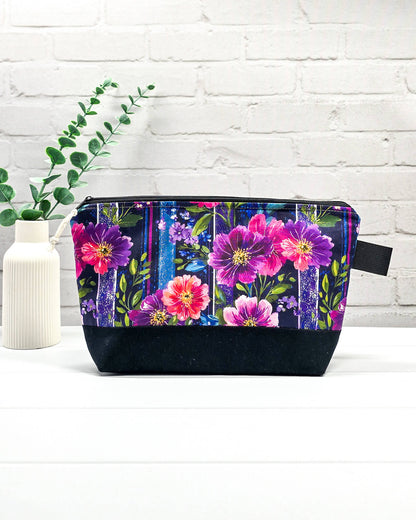 Stricktasche mit pink-violettem Blütenmuster auf Streifendekor, schwarzem Canvas-Boden und Reißverschluss. Platz für 200g Wolle. Handgenäht in Bayern von Nadelmikado.