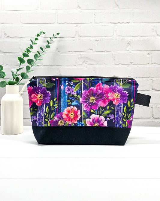 Stricktasche mit pink-violettem Blütenmuster auf Streifendekor, schwarzem Canvas-Boden und Reißverschluss. Platz für 200g Wolle. Handgenäht in Bayern von Nadelmikado.