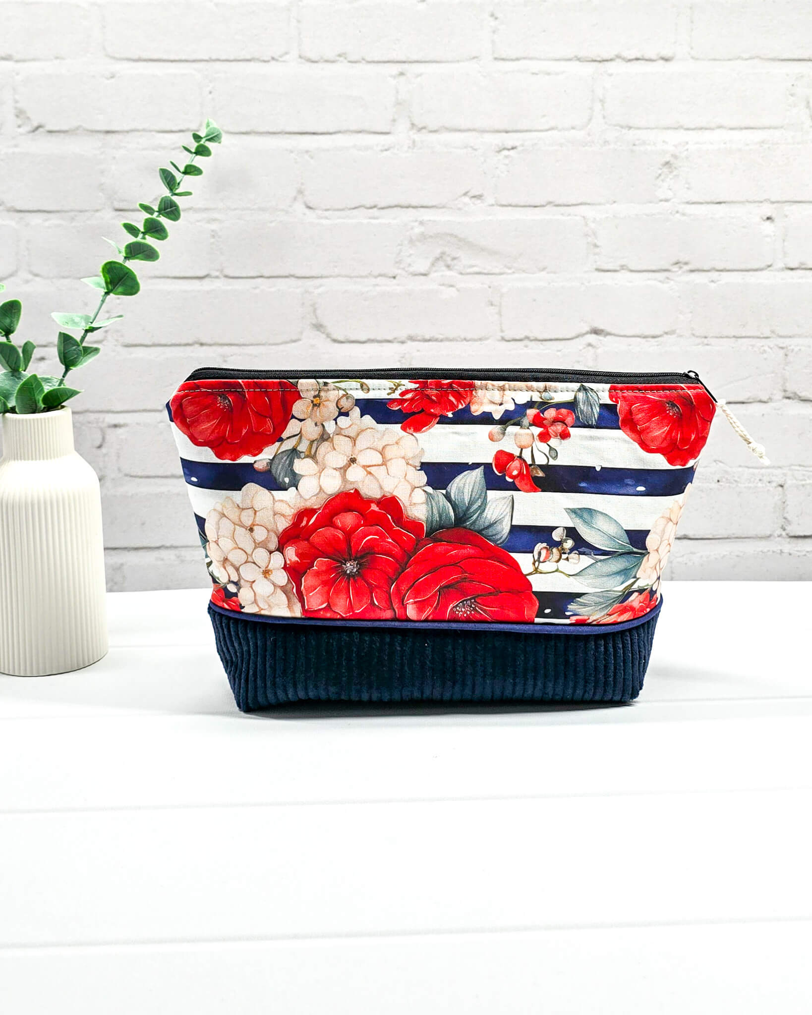 Handgemachte Projekttasche Isvind in Größe S mit roten Rosen auf blau-weiß gestreiftem Stoff und einem Taschenboden aus dunkelblauem Breitcord. Handgenäht in Bayern von Nadelmikado.