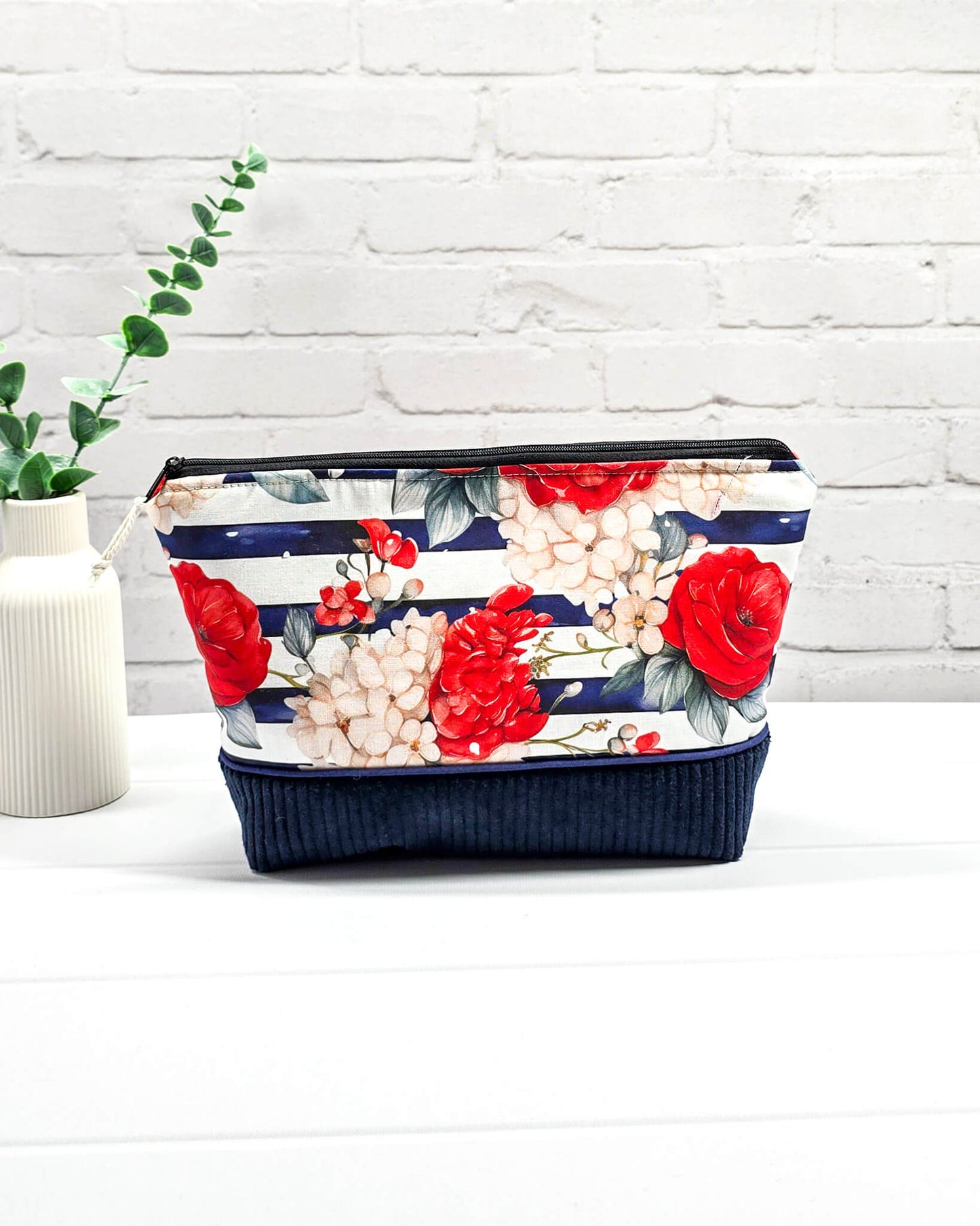 Handgemachte Projekttasche Isvind in Größe S mit roten Rosen auf blau-weiß gestreiftem Stoff und einem Taschenboden aus dunkelblauem Breitcord. Handgenäht in Bayern von Nadelmikado.