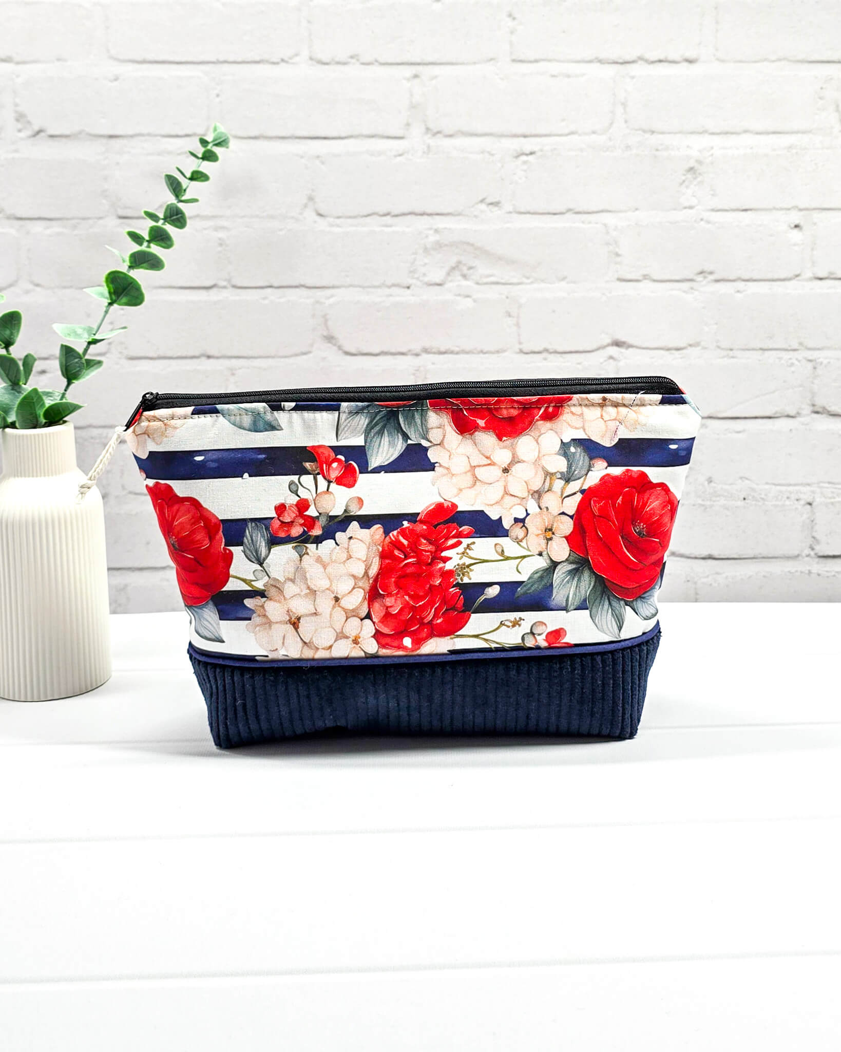 Handgemachte Projekttasche Isvind in Größe S mit roten Rosen auf blau-weiß gestreiftem Stoff und einem Taschenboden aus dunkelblauem Breitcord. Handgenäht in Bayern von Nadelmikado.