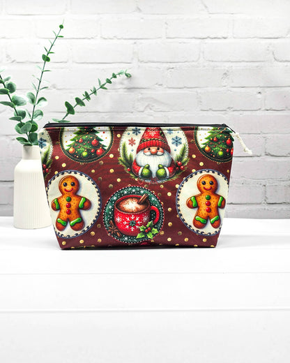 Projekttasche Isvind Größe S mit Weihnachtswichtel, Lebkuchenmännchen, geschmückten Tannenbäumen und roter Tasse auf dunkelrotem Stoff mit goldenen Punkten. Mit Reißverschluss für Strickprojekte bis 200 g Wolle. Handgenäht in Bayern von Nadelmikado.