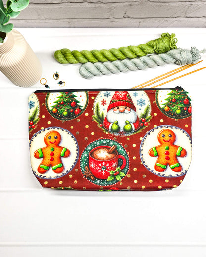 Projekttasche Isvind Größe S mit Weihnachtswichtel, Lebkuchenmännchen, geschmückten Tannenbäumen und roter Tasse auf dunkelrotem Stoff mit goldenen Punkten. Mit Reißverschluss für Strickprojekte bis 200 g Wolle. Handgenäht in Bayern von Nadelmikado.