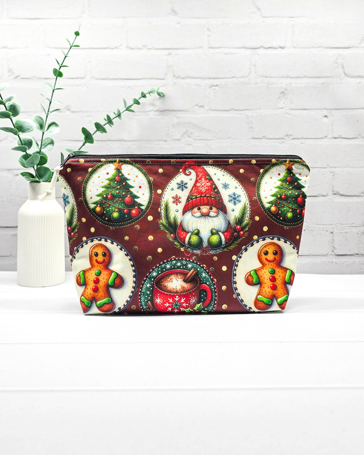 Projekttasche Isvind Größe S mit Weihnachtswichtel, Lebkuchenmännchen, geschmückten Tannenbäumen und roter Tasse auf dunkelrotem Stoff mit goldenen Punkten. Mit Reißverschluss für Strickprojekte bis 200 g Wolle. Handgenäht in Bayern von Nadelmikado.
