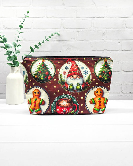 Projekttasche Isvind Größe S mit Weihnachtswichtel, Lebkuchenmännchen, geschmückten Tannenbäumen und roter Tasse auf dunkelrotem Stoff mit goldenen Punkten. Mit Reißverschluss für Strickprojekte bis 200 g Wolle. Handgenäht in Bayern von Nadelmikado.