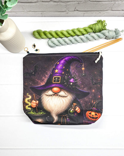 Projekttasche Isvind Größe S mit Halloweenwichtel, lila Hexenhut, weißem Bart, grün blubberndem Zaubertrank und orangefarbenem Kürbis auf dunklem Stoff. Mit Reißverschluss für kleine Strickprojekte. Handgenäht in Bayern von Nadelmikado.