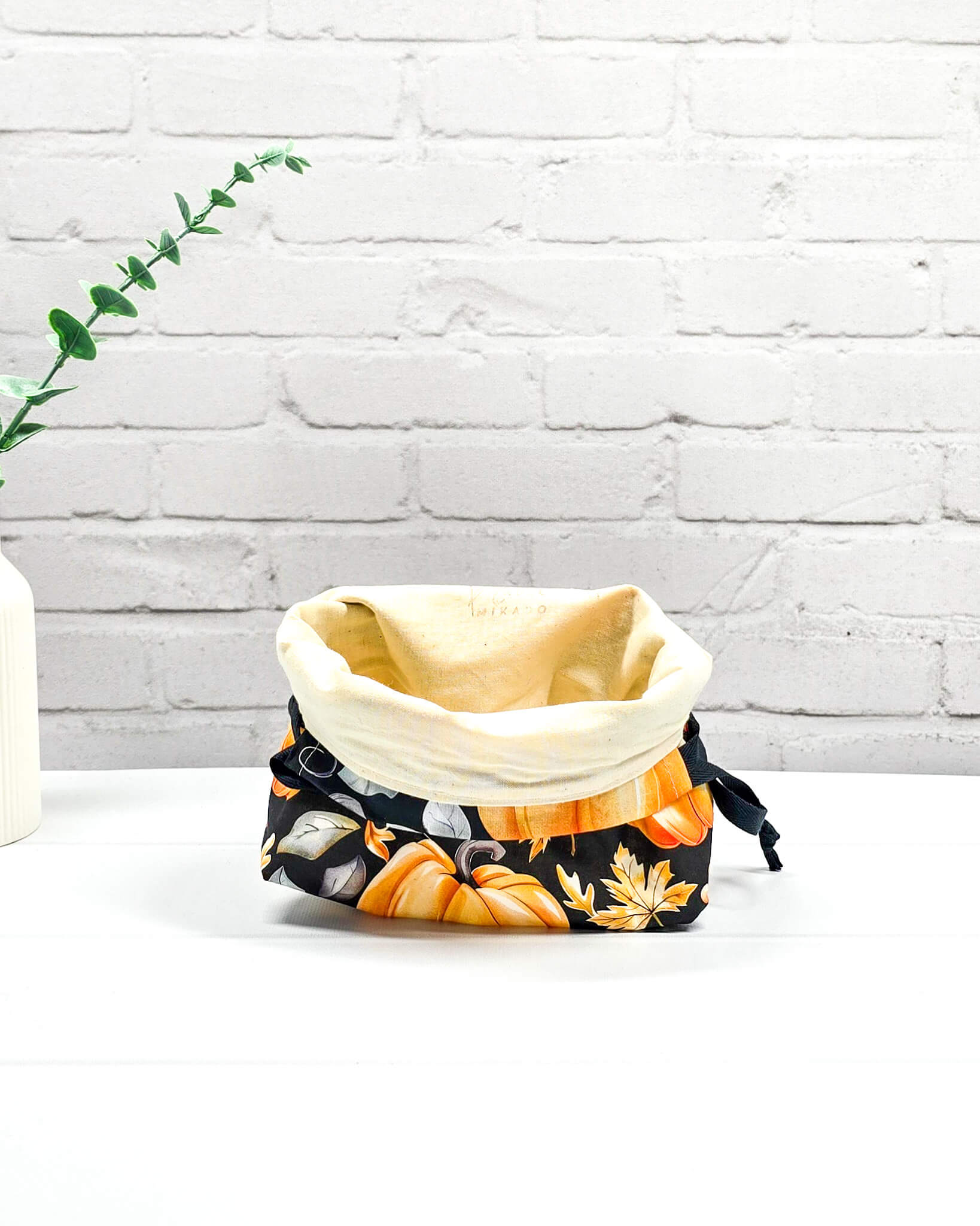 Projekttasche in Größe S für Sockenprojekte bis 100 g Wolle. Sicherer Kinchaku-Verschluss bewahrt das Strickzeug auf. Motiv mit großen orangen Kürbissen auf schwarzem Stoff. Handgenäht in Bayern von Nadelmikado