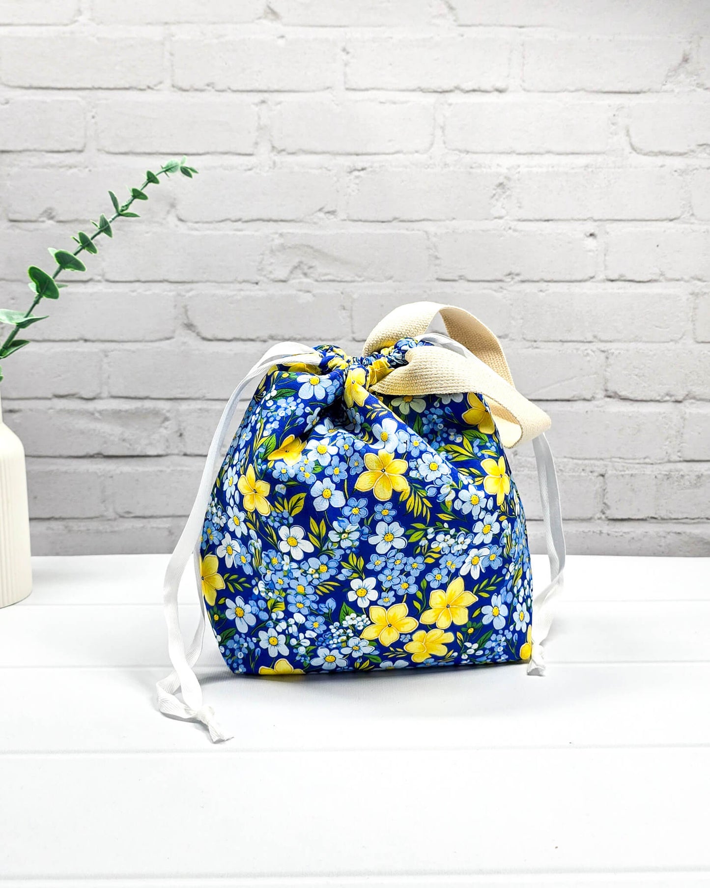 Handgefertigte Stricktasche mit gelben Blumen auf blauem Stoff, bietet Platz für 200g Wolle und Sockenstrickzeug, mit Baumwoll-Tragegurt - handgenäht in Bayern von Nadelmikado