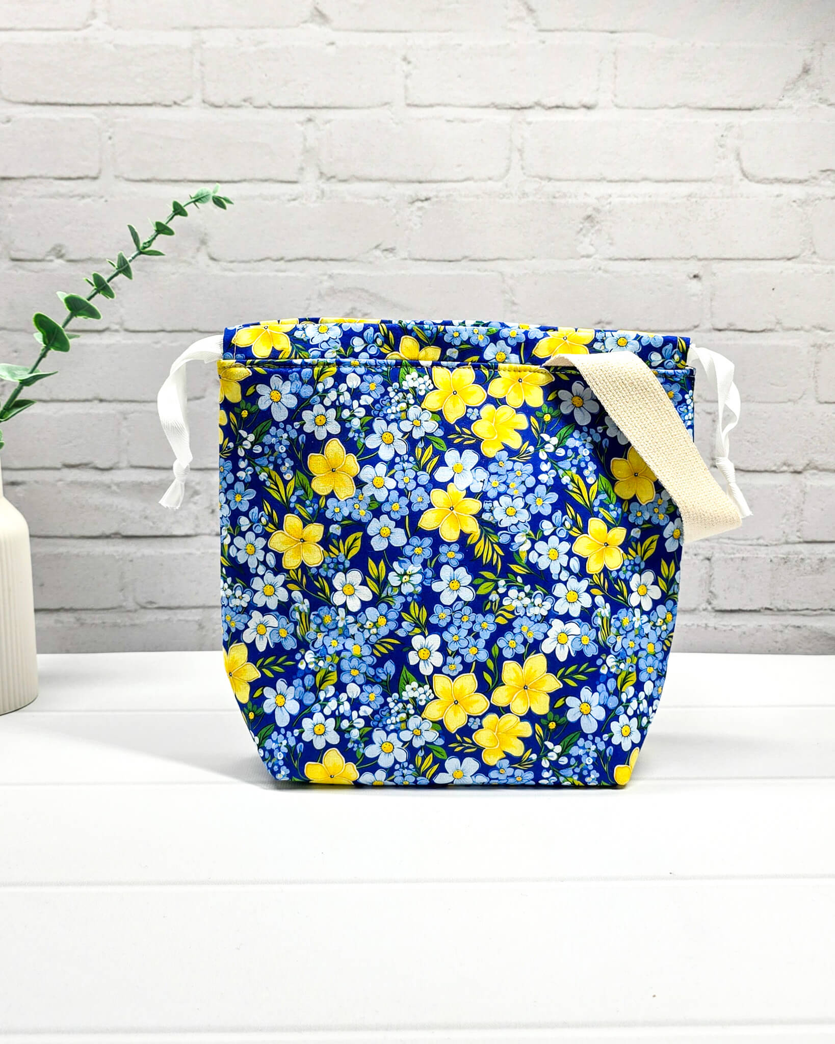 Handgefertigte Stricktasche mit gelben Blumen auf blauem Stoff, bietet Platz für 200g Wolle und Sockenstrickzeug, mit Baumwoll-Tragegurt - handgenäht in Bayern von Nadelmikado