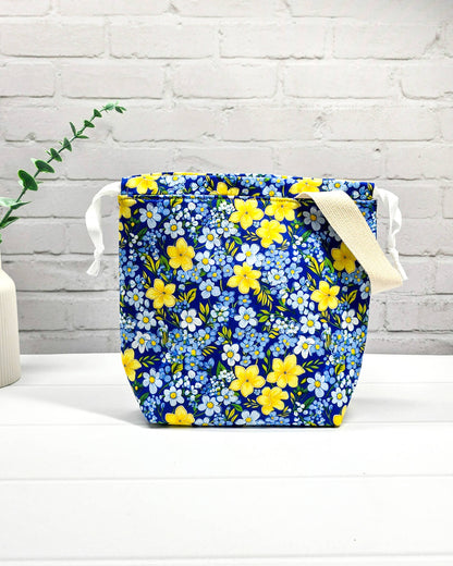 Handgefertigte Stricktasche mit gelben Blumen auf blauem Stoff, bietet Platz für 200g Wolle und Sockenstrickzeug, mit Baumwoll-Tragegurt - handgenäht in Bayern von Nadelmikado