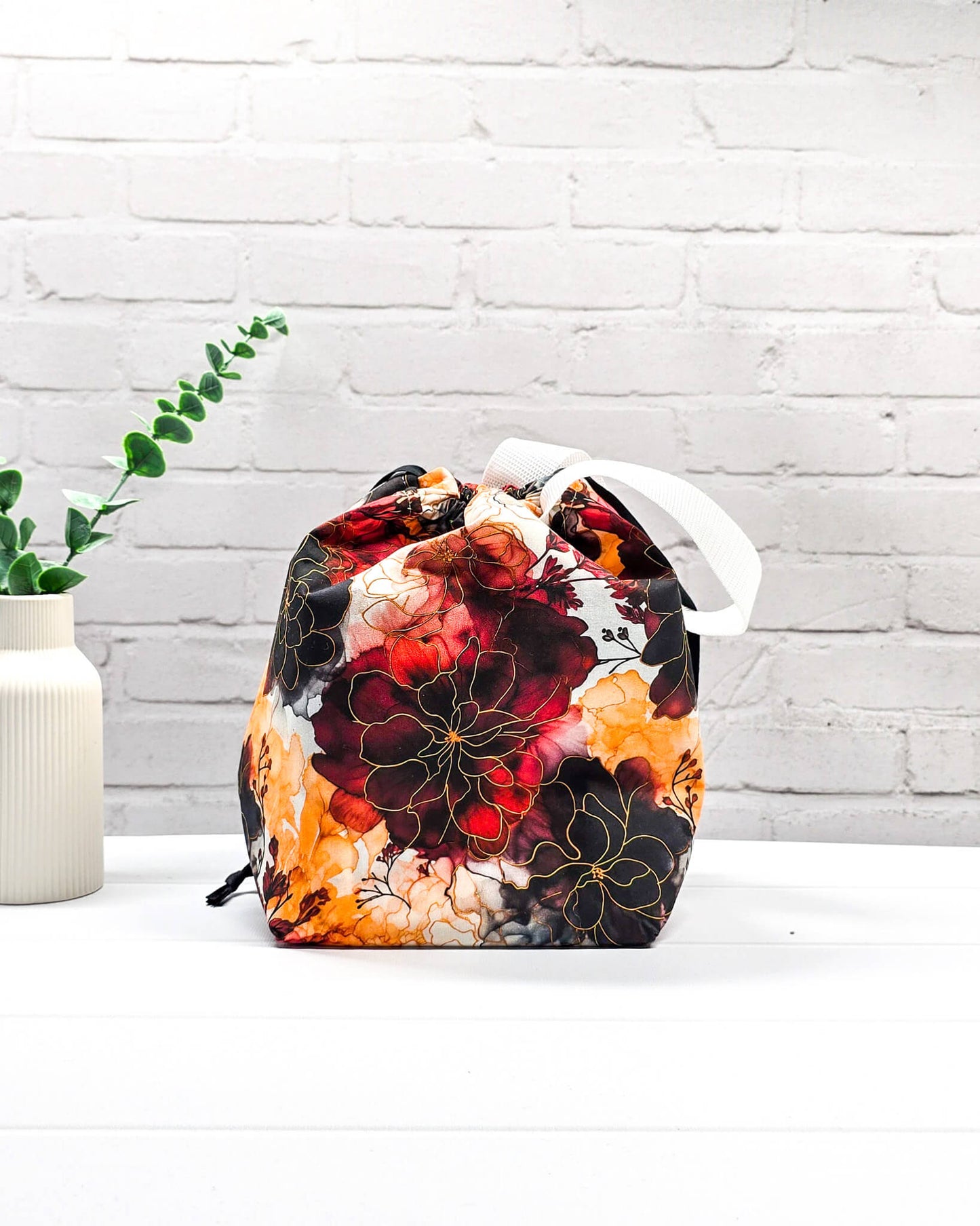 Projekttasche Tuva M aus Baumwolle mit weinroten und senfgelben Aquarell-Blumen, schwarzem Kordelzug und heller Schlaufe. Handgenäht in Bayern von Nadelmikado. 